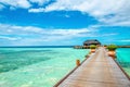 Wooden bridge leading to an exotic bungalow on the background of azure water, maldives Royalty Free Stock Photo