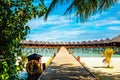 Wooden bridge leading to an exotic bungalow on the background of azure water, maldives Royalty Free Stock Photo
