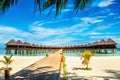 Wooden bridge leading to an exotic bungalow on the background of azure water, maldives Royalty Free Stock Photo