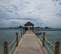 A wooden bridge leading to gazebo with villager house in the background Royalty Free Stock Photo