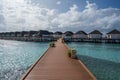 A wooden bridge leading to the houses on stilts above sea level. There are flowers on the bridge Royalty Free Stock Photo