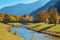 Wooden bridge over calm river in an autumn park with orange trees in the mountains in Alps Royalty Free Stock Photo