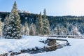 Wooden bridge over a creek in a snowy forested mountain landscape Royalty Free Stock Photo