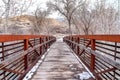 Wooden bridge over creek in the mountain with leafless trees on snowy winter day Royalty Free Stock Photo