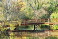 Wooden bridge over mirrored lake in the beautiful autumn park Royalty Free Stock Photo