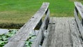 A wooden bridge over a pond with green grass in the background Royalty Free Stock Photo