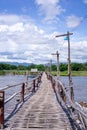 The wooden bridge over the river has a forested background. Mountains and blue skies Royalty Free Stock Photo