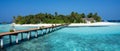 Wooden bridge over the sea leading to an island with sandy beaches and a green forest. Palm trees Royalty Free Stock Photo