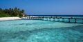 Wooden bridge over the sea leading to an island with sandy beaches and a green forest. Palm trees Royalty Free Stock Photo