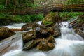 wooden bridge over a wild mountain creek with huge rocks Royalty Free Stock Photo