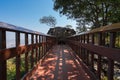 Wooden bridge pedestrian walkway to big rock with small hold cave on forest hill with blue sky