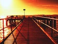 Wooden bridge at the sea at sunset. Windless weather, peaceful silent day in bay. Royalty Free Stock Photo