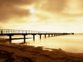 Wooden bridge at the sea at sunset. Windless weather, peaceful silent day in bay. Royalty Free Stock Photo