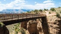A wooden bridge spans a deep canyon with red rock cliffs and a blue sky with clouds in the background Royalty Free Stock Photo