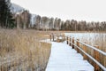 Wooden bridge trail along the shoreline of the lake covered of the first snow. Royalty Free Stock Photo