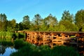 A wooden bridge of tree logs lies across a small river inside a wooded area among green nature. Royalty Free Stock Photo