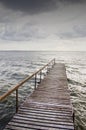 Wooden bridge on wavy lake. Dark sky before storm Royalty Free Stock Photo