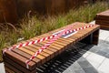 Wooden brown bench with `No Sitting` sign in english and arabic and red and white barricade tape, safety measures due to COVID. Royalty Free Stock Photo