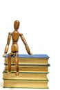 Wooden brown mannequin sits stack of books.Concept reading books.