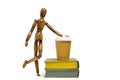 Wooden brown mannequin stands next books and glass of coffee.Concept reading books.