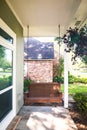 A wooden brown outdoor porch swing on a small front porch of a house Royalty Free Stock Photo