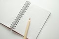 Wooden brown pencil on the background of a blank notepad