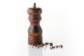 Wooden brown pepper mill with black peppercorns on white background Royalty Free Stock Photo