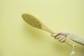 wooden brush for dry anti-cellulite massage for the body and legs or combing in the girl's hand. Beauty concept. Royalty Free Stock Photo