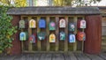 Wooden building having multiple mailboxes of different colors attached to it Royalty Free Stock Photo
