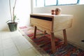 Wooden bureau on a colorful rug, side table, night table, natural light entrance