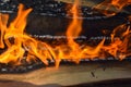 Wooden burning hot charred planks of wood logs in a fire with tongues of fire and smoke. Texture, background Royalty Free Stock Photo