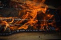 Wooden burning hot charred planks of wood logs in a fire with tongues of fire and smoke. Texture, background Royalty Free Stock Photo