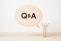 Wooden businessman icon with dialogue frame Q & A on wooden desktop and white background