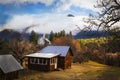 Wooden cabin in the foggy mountains at golden hour with smoke rising from stovepipe and truck parked outside