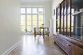 Wooden cabinet in bright dining room interior with white chairs Royalty Free Stock Photo