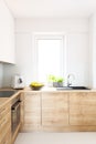 Wooden cabinets in bright minimal white kitchen interior with wi