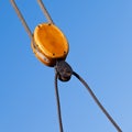 Wooden cable pulley rigging detail against blue sky