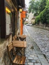 Wooden cafe table and chairs squeezed onto narrow sidewalk in Paris, France