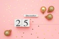Wooden calendar December 25, golden christmas balls and star confetti on pink background. Merry christmas concept. Top view Flat Royalty Free Stock Photo