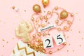 Wooden calendar December 25, textile christmas cactus, golden baubles, stars confetti on pink background. Merry Royalty Free Stock Photo