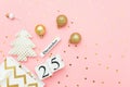 Wooden calendar December 25, textile christmas tree, golden baubles, stars confetti on pink background. Merry christmas concept. Royalty Free Stock Photo