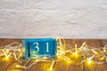 Wooden calendar with 31 december word on glowing garland background, New Year holiday Royalty Free Stock Photo