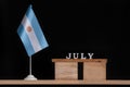 Wooden calendar of Jule with Argentine flag on black background. Holidays of Argentina in Jule Royalty Free Stock Photo