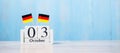 Wooden calendar of October 3rd with miniature Germany flags. German Unity Day and happy celebration concepts