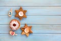 Wooden candlesticks in the shape of star, donut and dreidels on background of blue painted wooden planks with space for text.