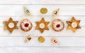 Wooden candlesticks in the shape of star, donut, golden chocolate coins and dreidels on background of white painted wooden planks Royalty Free Stock Photo