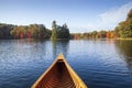 Wooden canoe moves on a blue lake with trees in autumn color and a small island in northern Minnesota Royalty Free Stock Photo