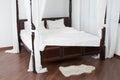 Wooden canopy bed and a white hide on the floor Royalty Free Stock Photo