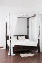 Wooden canopy bed and a white hide on the floor Royalty Free Stock Photo