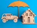 Wooden car and house under umbrella protection and insurance Royalty Free Stock Photo